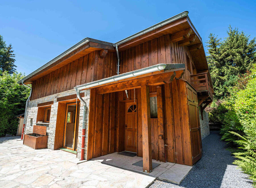 Experience rustic charm in this wooden chalet, featuring a stone base and a welcoming covered entrance.