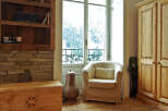 This charming property boasts a cozy living space with a comfortable armchair and a stunning view through the large windows.