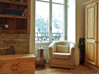 This charming property boasts a cozy living space with a comfortable armchair and a stunning view through the large windows.