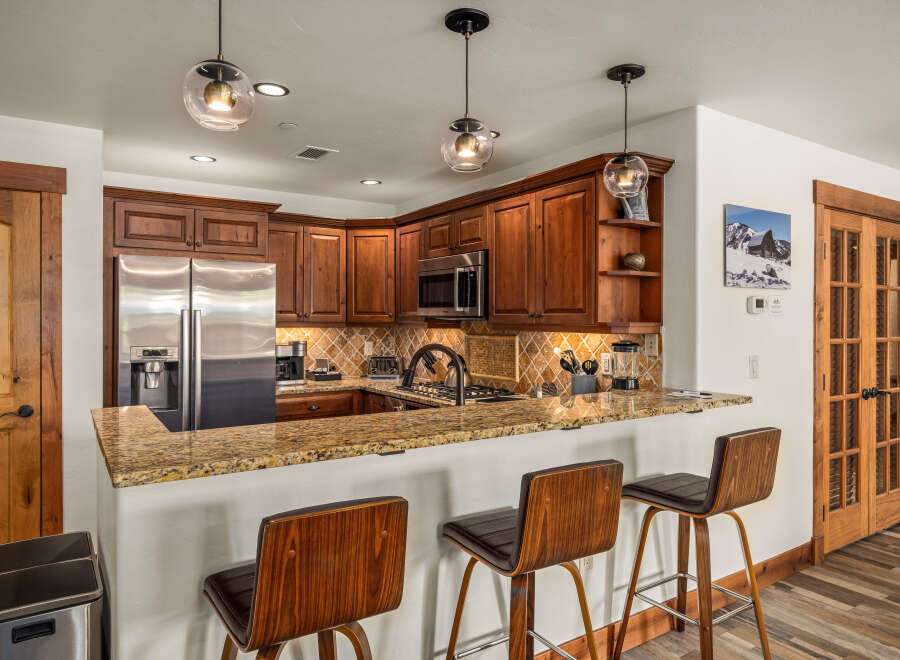 This stunning kitchen boasts beautiful wooden cabinetry, stainless steel appliances, and a granite countertop, creating a warm and inviting atmosphere.