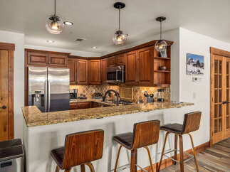 This stunning kitchen boasts beautiful wooden cabinetry, stainless steel appliances, and a granite countertop, creating a warm and inviting atmosphere.