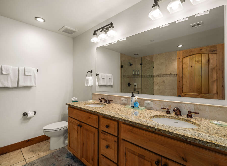 This stunning bathroom boasts a luxurious double vanity with a granite countertop, offering ample space for your daily routines.