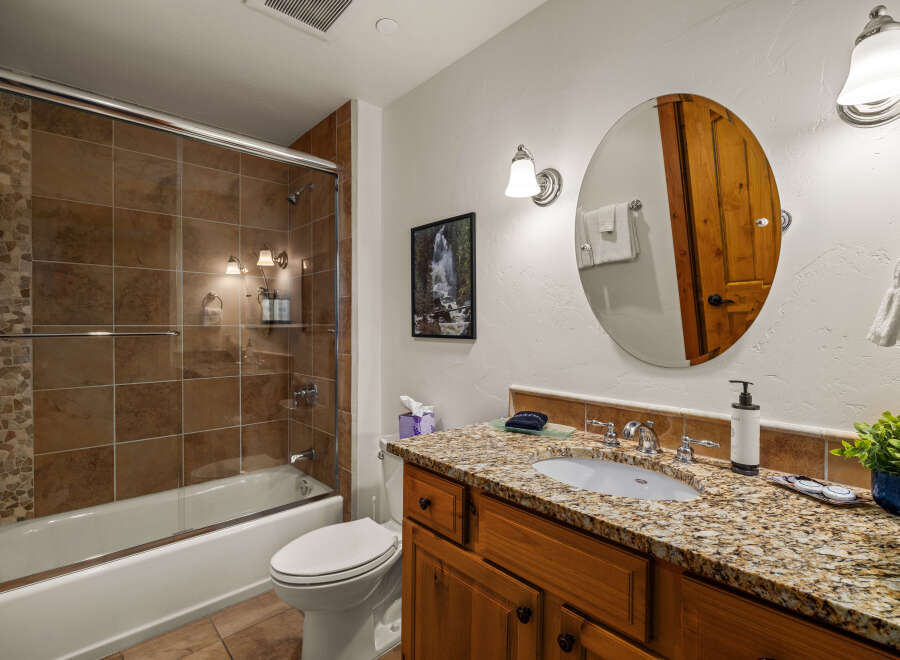 This stunning bathroom boasts a luxurious feel with its granite countertops and rich wooden cabinetry.