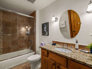 This stunning bathroom boasts a luxurious feel with its granite countertops and rich wooden cabinetry.
