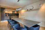 This modern dining area boasts a sleek, long wooden table perfect for gatherings.