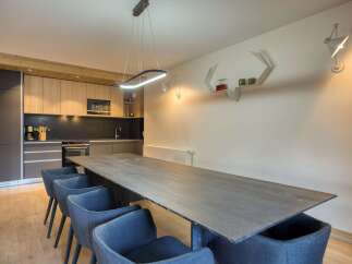 This modern dining area boasts a sleek, long wooden table perfect for gatherings.