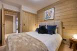 This cozy bedroom features a rustic wood-paneled wall and a comfortable bed with plush pillows.