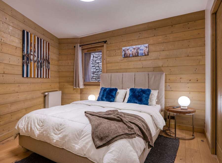 This cozy bedroom features a rustic wooden wall design, creating a warm and inviting atmosphere.