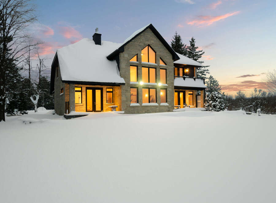 This stunning stone house is nestled in a winter wonderland, offering a serene and picturesque setting.