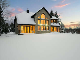 This stunning stone house is nestled in a winter wonderland, offering a serene and picturesque setting.