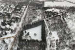 This aerial view showcases a stunning winter landscape, highlighting a unique property surrounded by a lush evergreen forest.