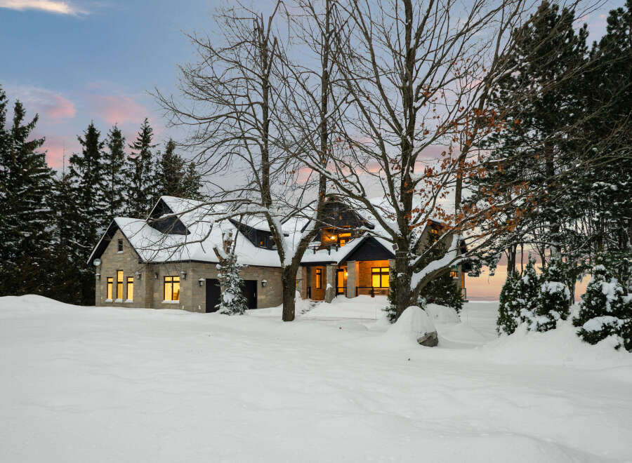 This stunning property showcases a beautiful stone house nestled in a winter wonderland.