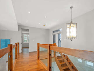This stunning property features a modern staircase with glass panels and warm wooden accents, creating an inviting and stylish atmosphere.