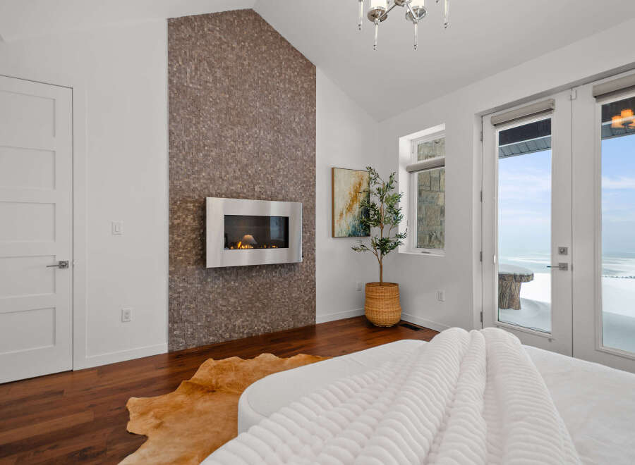 Experience luxury in this stunning bedroom featuring a modern fireplace and a unique accent wall.