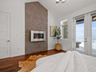Experience luxury in this stunning bedroom featuring a modern fireplace and a unique accent wall.