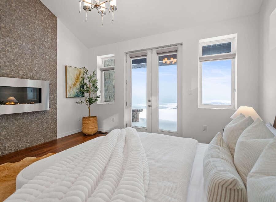 Experience luxury in this stunning bedroom featuring a modern fireplace and a cozy bed.