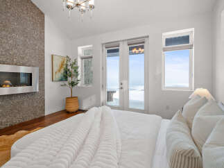 Experience luxury in this stunning bedroom featuring a modern fireplace and a cozy bed.