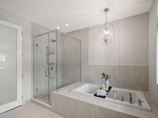 Step into luxury with this stunning bathroom featuring a sleek glass shower and a relaxing soaking tub.