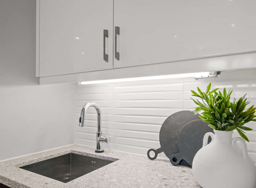 This modern kitchen boasts sleek white cabinetry and a stylish stainless steel faucet.