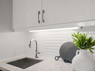 This modern kitchen boasts sleek white cabinetry and a stylish stainless steel faucet.