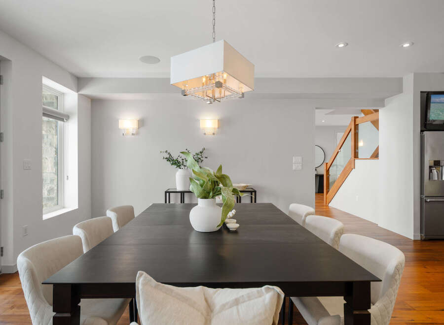 This stunning dining room showcases a modern aesthetic with its sleek, dark wood dining table and elegant white chairs.