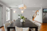 This stunning dining room showcases a modern aesthetic with its sleek, dark wood dining table and elegant white chairs.