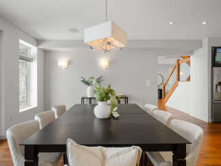 This stunning dining room showcases a modern aesthetic with its sleek, dark wood dining table and elegant white chairs.