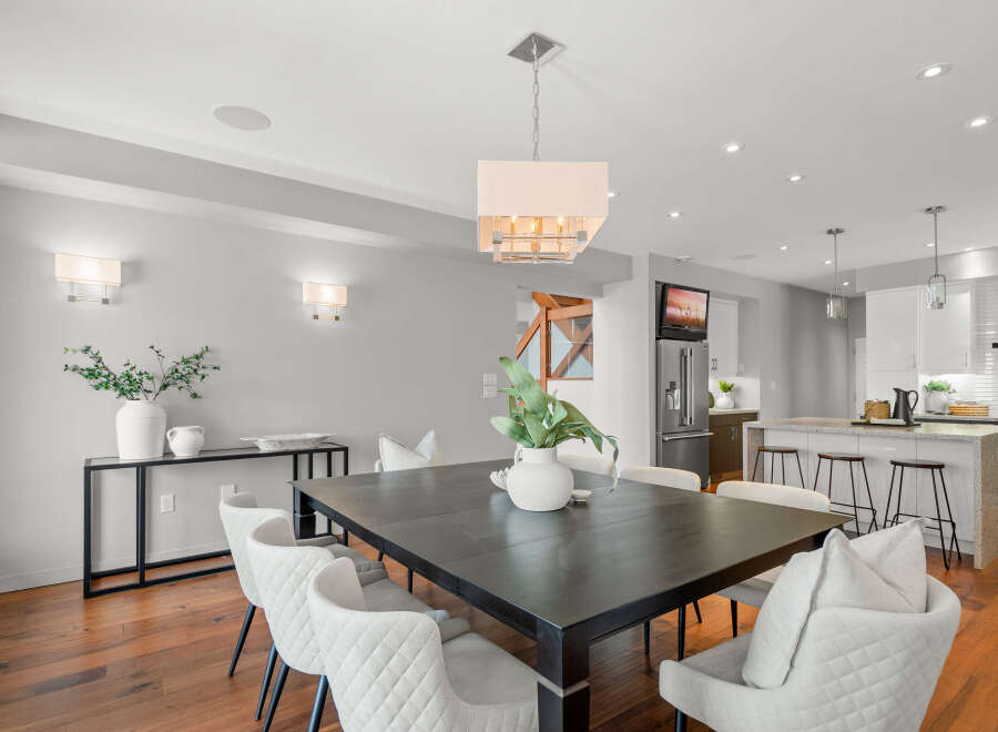 This stunning dining room showcases a modern aesthetic with its sleek, dark wood dining table and elegant white chairs.