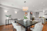 This stunning dining room showcases a modern aesthetic with its sleek, dark wood dining table and elegant white chairs.