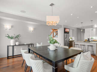 This stunning dining room showcases a modern aesthetic with its sleek, dark wood dining table and elegant white chairs.