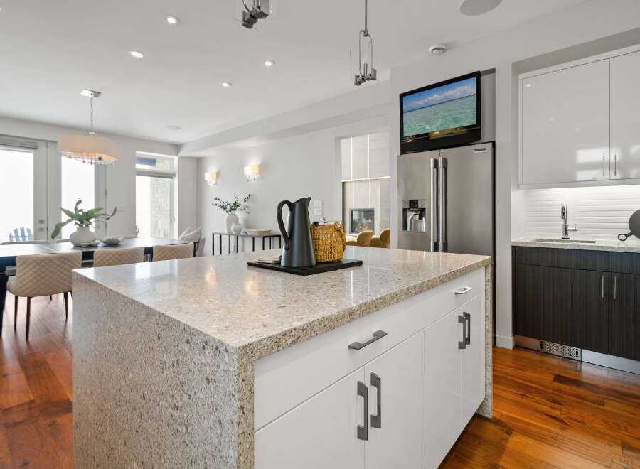 This stunning kitchen boasts a modern design with sleek white cabinetry and a spacious granite countertop island, perfect for meal preparation and entertaining.