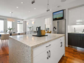 This stunning kitchen boasts a modern design with sleek white cabinetry and a spacious granite countertop island, perfect for meal preparation and entertaining.