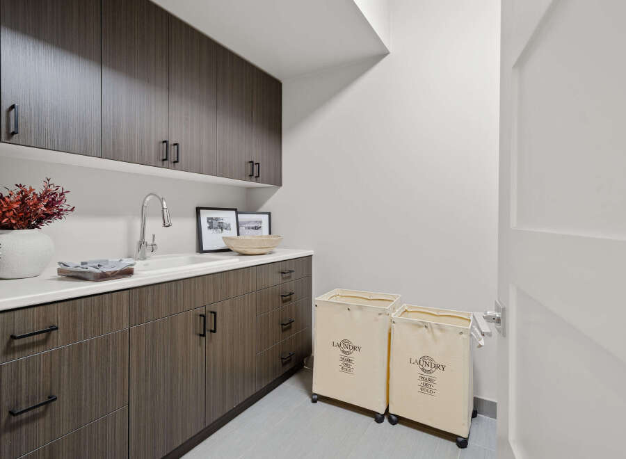 This modern laundry room boasts sleek cabinetry and a pristine white countertop, offering ample storage and workspace.