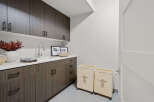 This modern laundry room boasts sleek cabinetry and a pristine white countertop, offering ample storage and workspace.