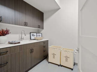 This modern laundry room boasts sleek cabinetry and a pristine white countertop, offering ample storage and workspace.