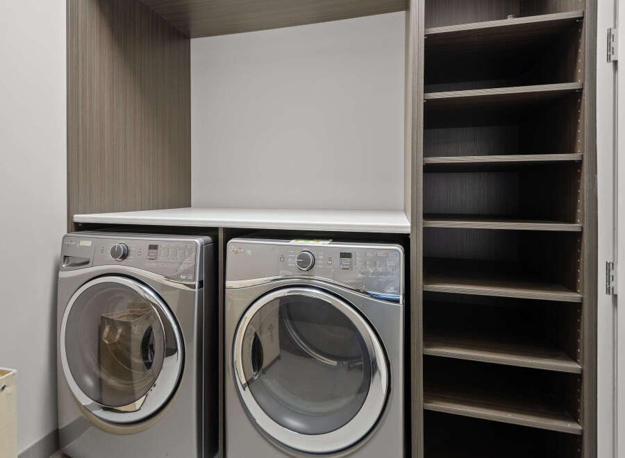 This laundry room features a modern design with a sleek countertop and ample storage space.