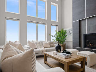 Experience luxury living in this stunning property, featuring a spacious living room with high ceilings and large windows that flood the space with natural light.