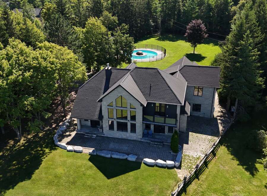 Experience luxury living in this stunning stone home, featuring a modern dark roof and expansive windows that flood the interior with natural light.