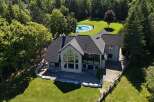 Experience luxury living in this stunning stone home, featuring a modern dark roof and expansive windows that flood the interior with natural light.