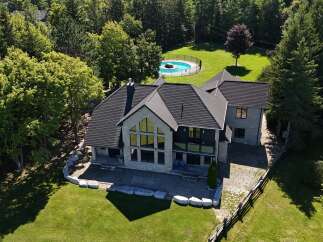Experience luxury living in this stunning stone home, featuring a modern dark roof and expansive windows that flood the interior with natural light.