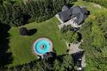 Discover this stunning property featuring a large, circular swimming pool with a central fountain, surrounded by lush green lawns and mature trees.
