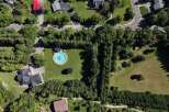 Discover this stunning aerial view showcasing a luxurious estate with a circular pool and a modern dark-roofed home.