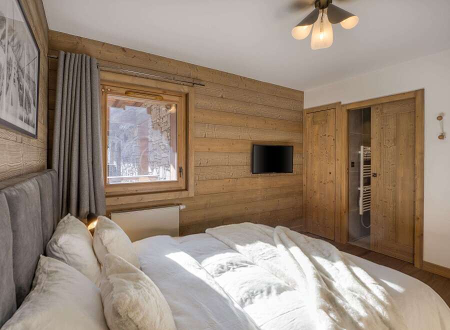 This cozy bedroom features a rustic wooden wall and a comfortable bed, perfect for a relaxing stay.