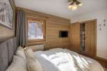 This cozy bedroom features a rustic wooden wall and a comfortable bed, perfect for a relaxing stay.