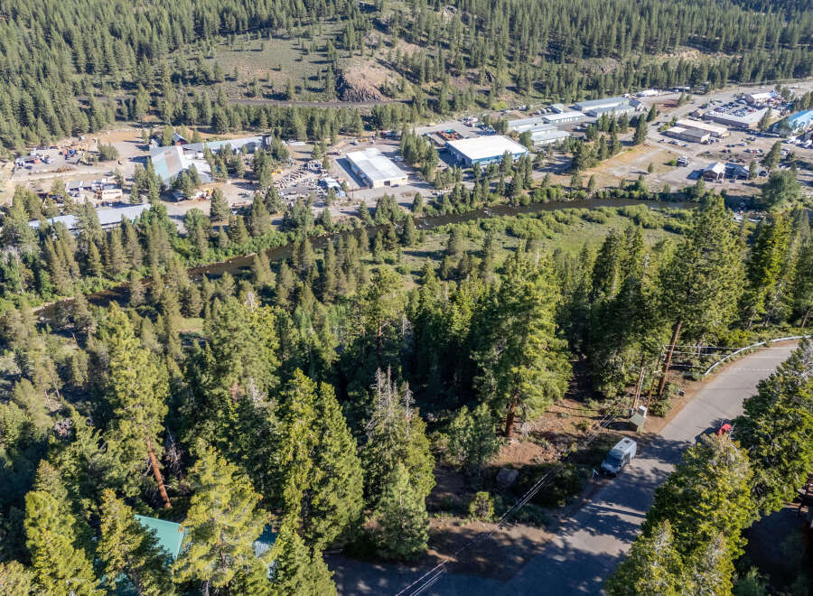 An aerial view showcases a picturesque mountain town nestled amidst lush greenery and towering trees.
