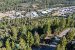 An aerial view showcases a picturesque mountain town nestled amidst lush greenery and towering trees.
