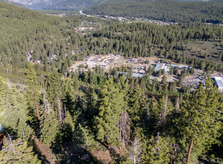 An aerial view showcases a lush, forested landscape, potentially indicating a property with significant natural surroundings.