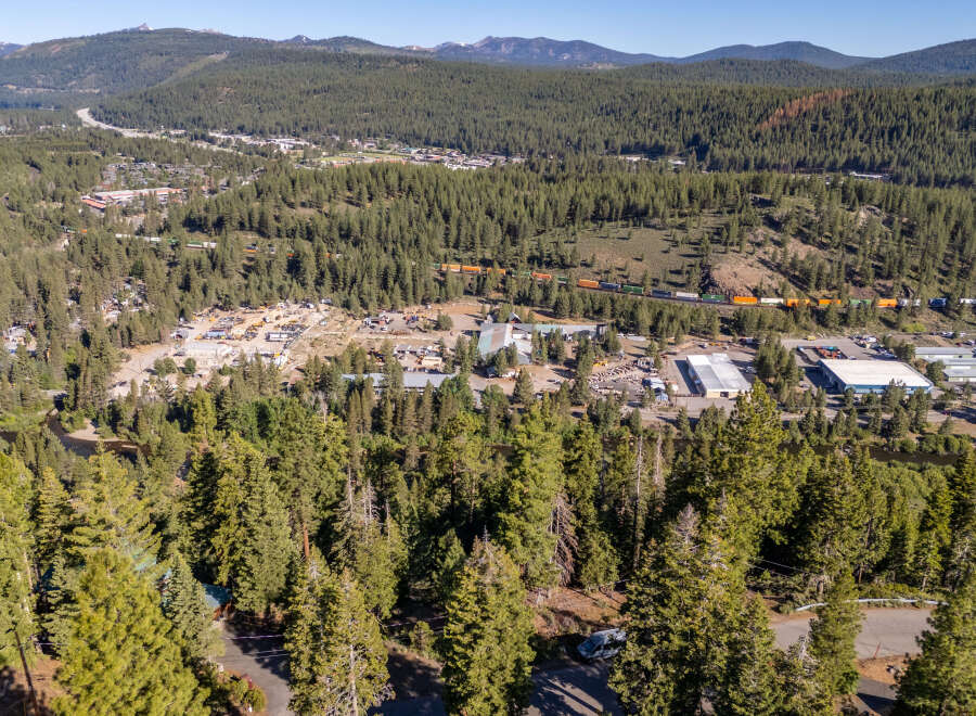 An aerial view showcases a picturesque landscape with lush greenery and a charming town nestled amidst the trees.