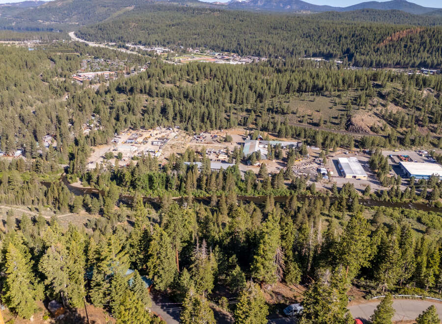 An aerial view showcases a lush, forested landscape with a winding river and a small town nestled in the distance.