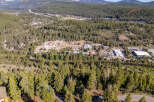 An aerial view showcases a lush, forested landscape with a winding river and a small town nestled in the distance.